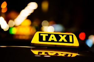 Lit up taxi sign on at night.